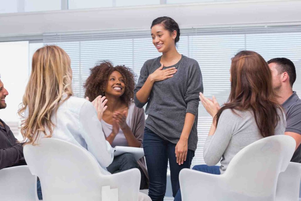 Woman speaking in a group therapy session while others listen and support her