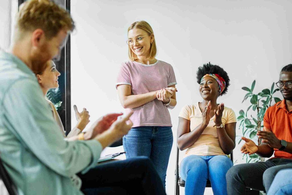 Mental health therapy group applauds as a participant shares progress during a supportive counseling session.