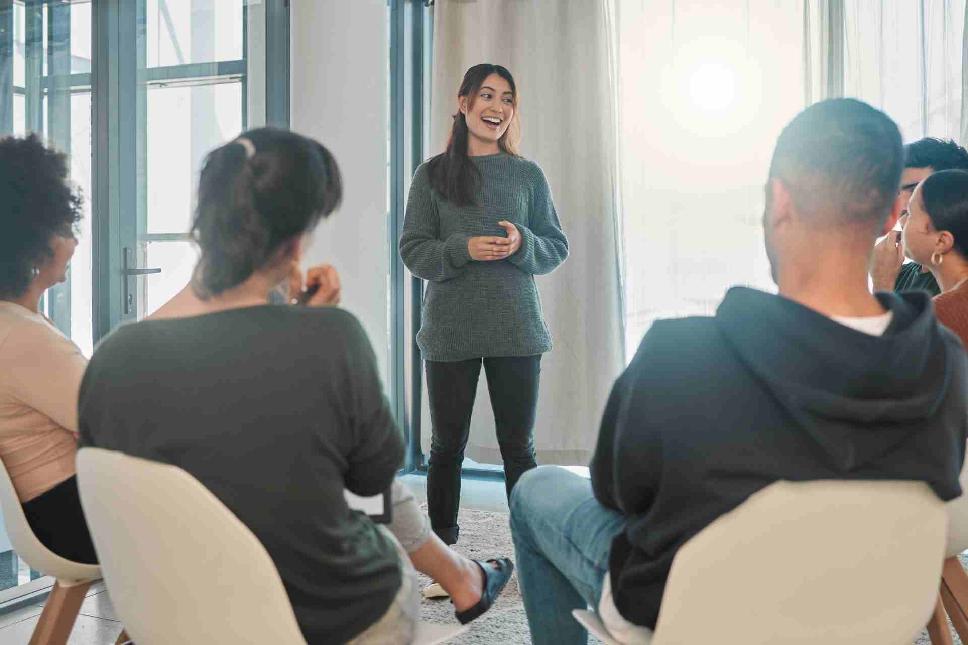 A participant speaks during a supportive group therapy session while others listen in a mental health treatment program.