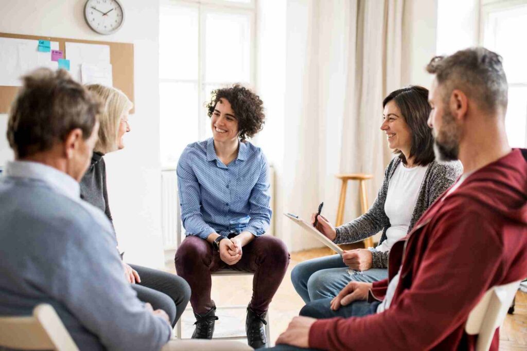 Mental health therapist leading a group therapy session with adults in a supportive treatment program.