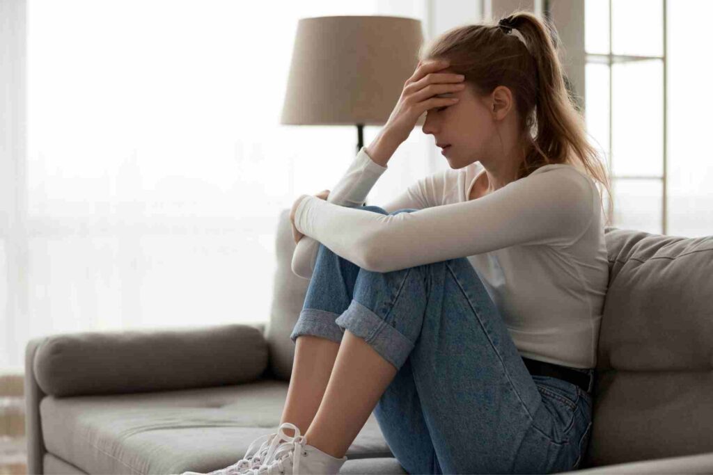Woman holding her head while experiencing overwhelming anxiety and emotional distress at home