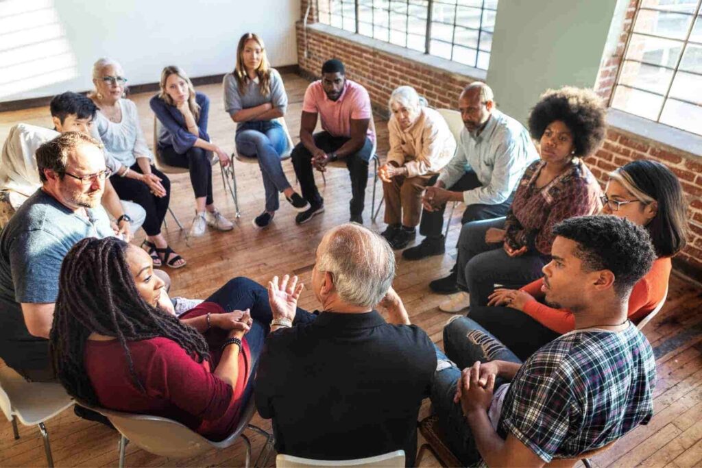 A licensed therapist facilitates a diverse group therapy session where participants discuss mental health in a supportive environment.