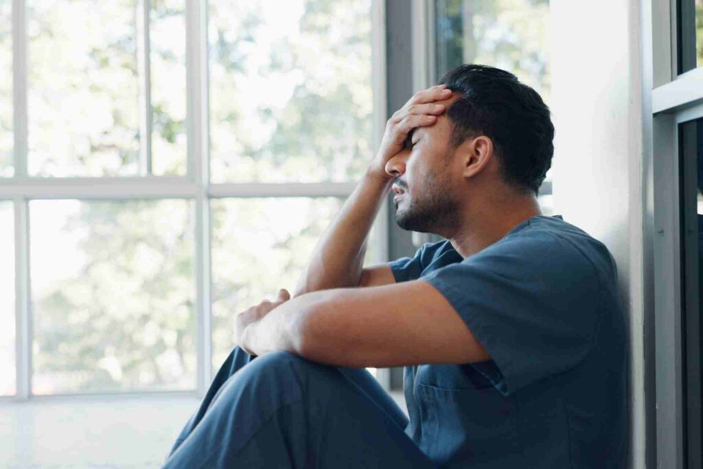 Professional experiencing mental health burnout while sitting alone with visible signs of emotional exhaustion and stress.