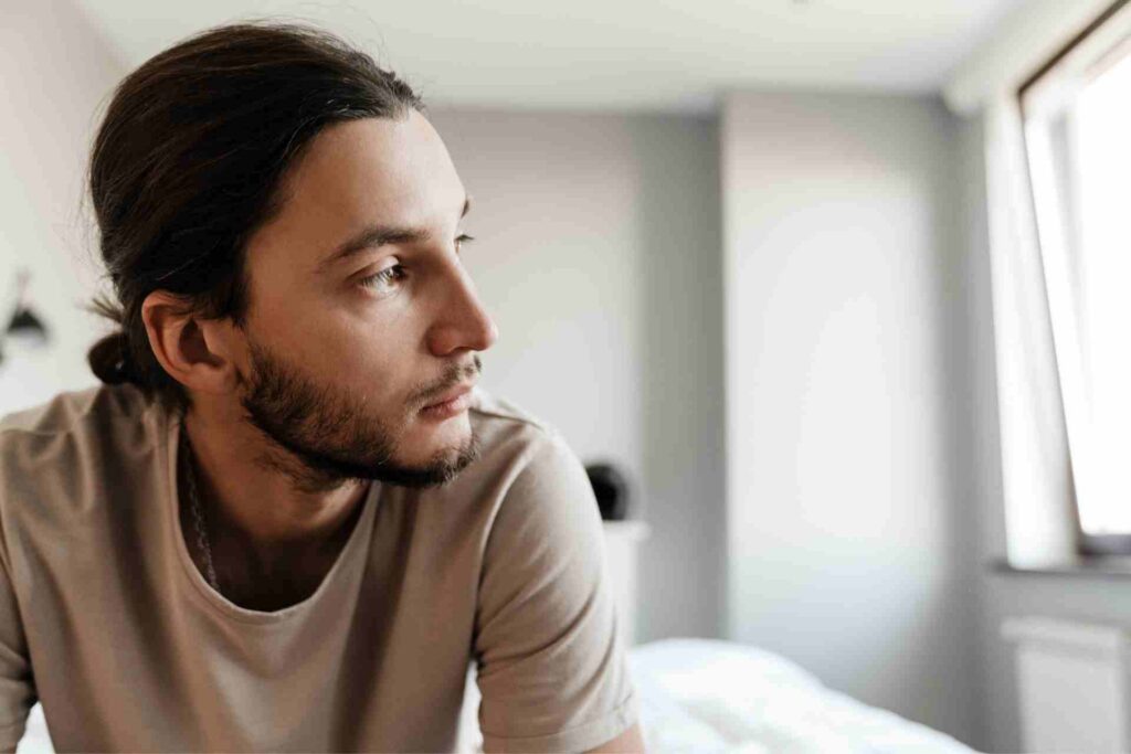 Young man sitting alone while experiencing symptoms of depression