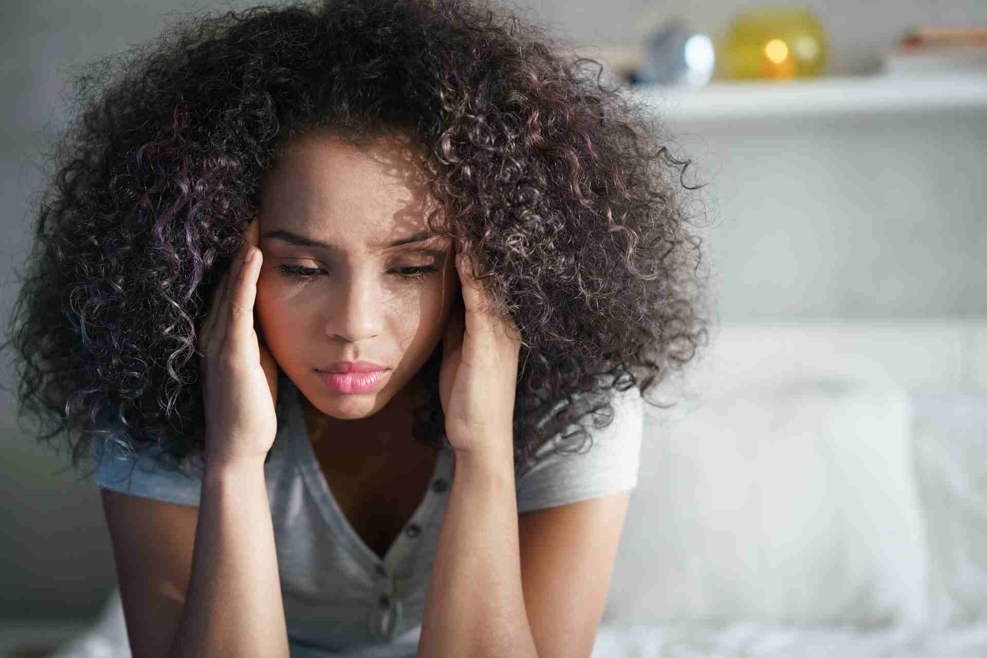 Woman sitting on a couch managing anxious thoughts and emotional stress
