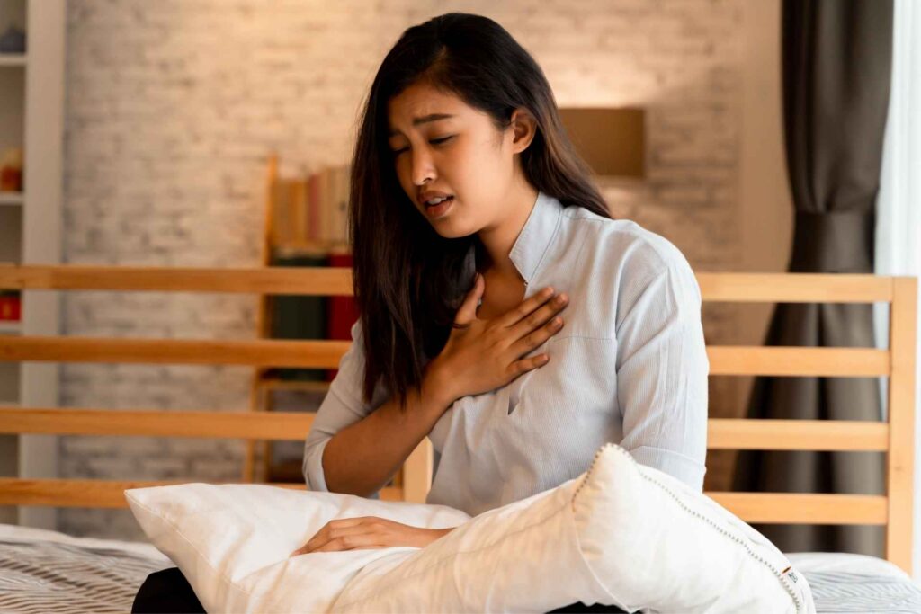 Woman holding her chest while experiencing shortness of breath that may be related to anxiety.