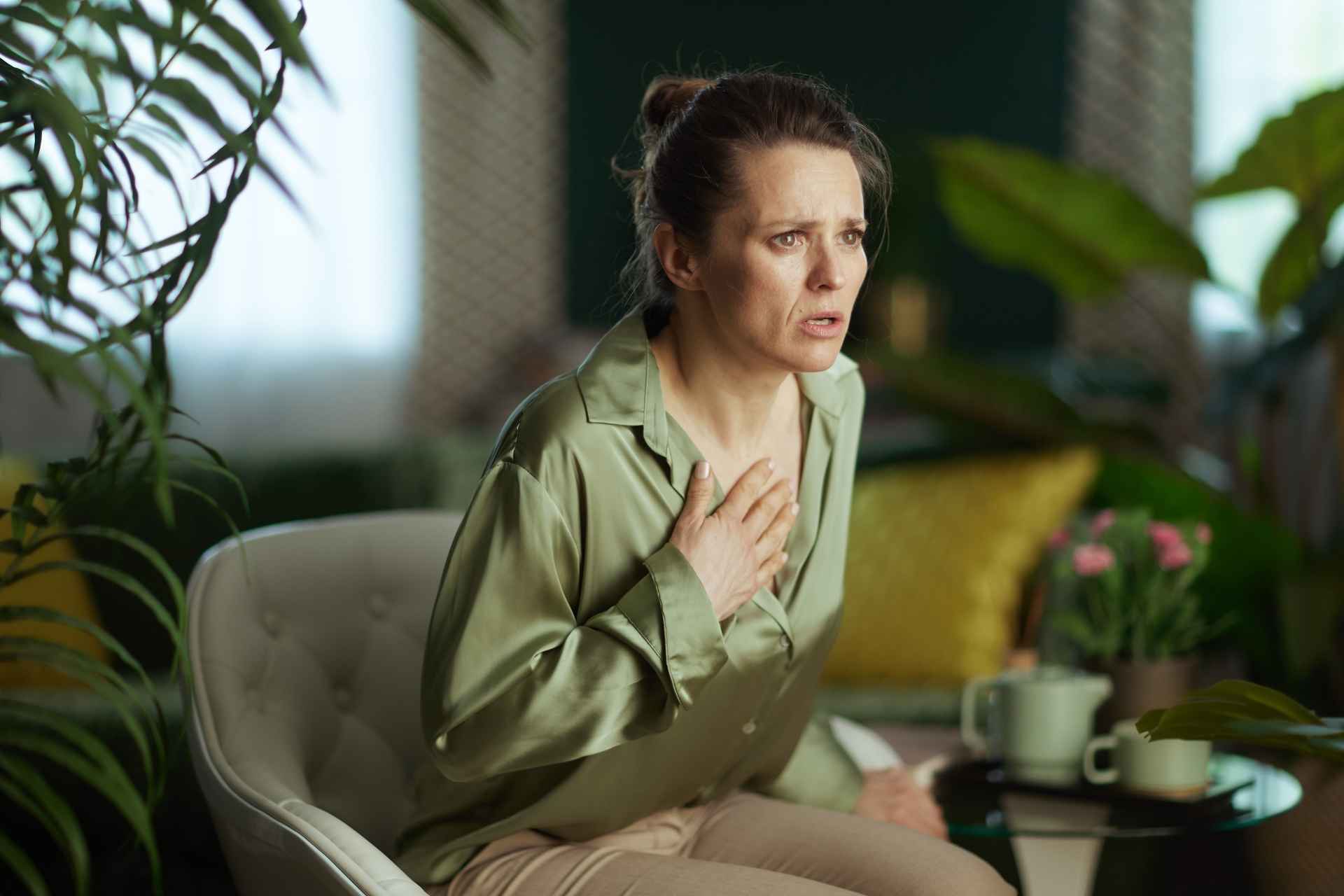 Woman holding her chest during an anxious episode with possible breathing difficulty.
