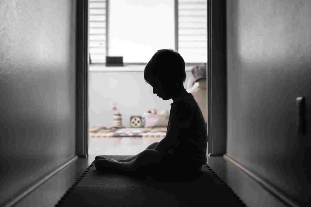 Child sitting alone in a hallway, representing the emotional effects of childhood trauma.