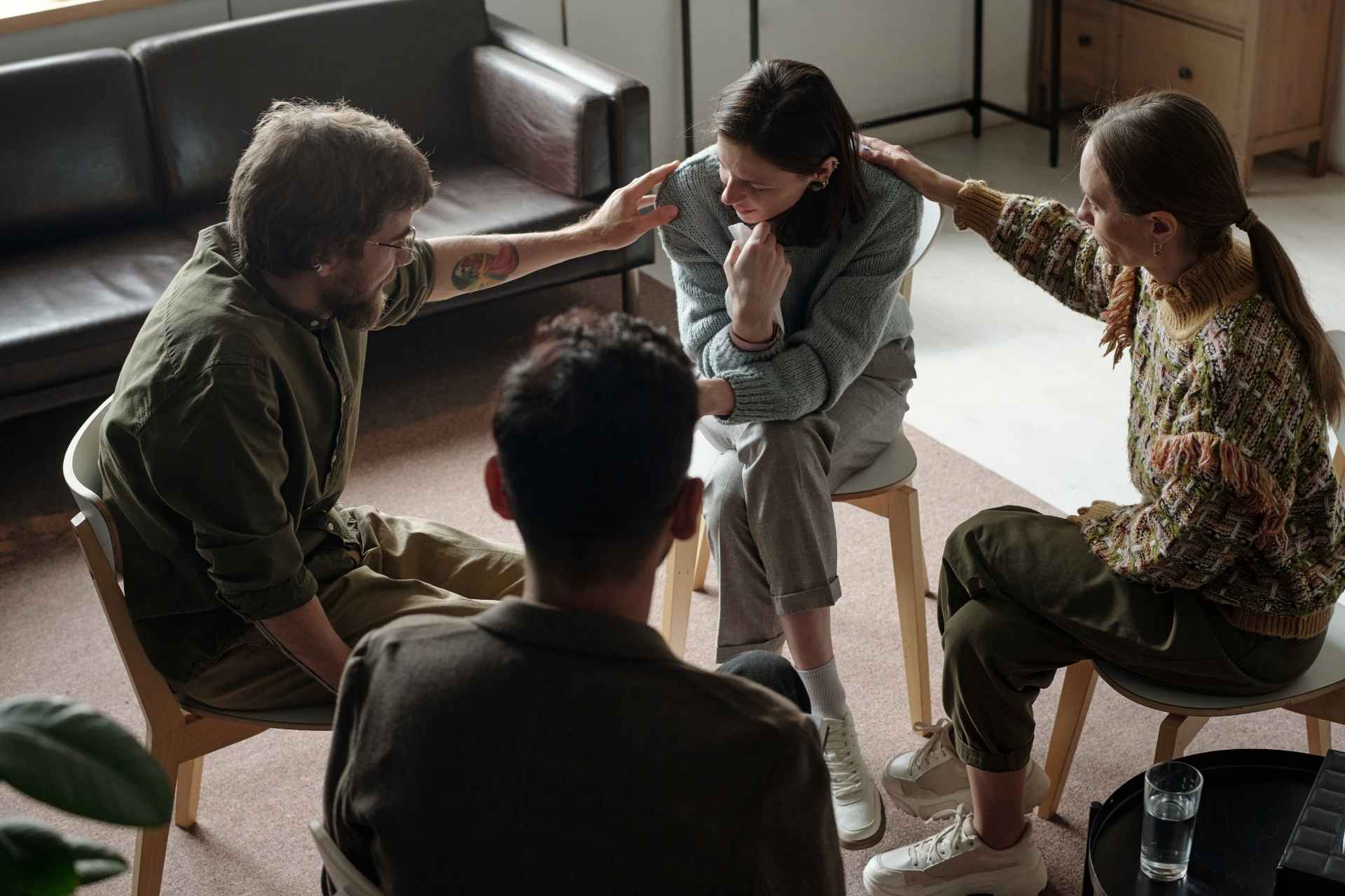 Group therapy participants supporting a woman experiencing emotional distress.